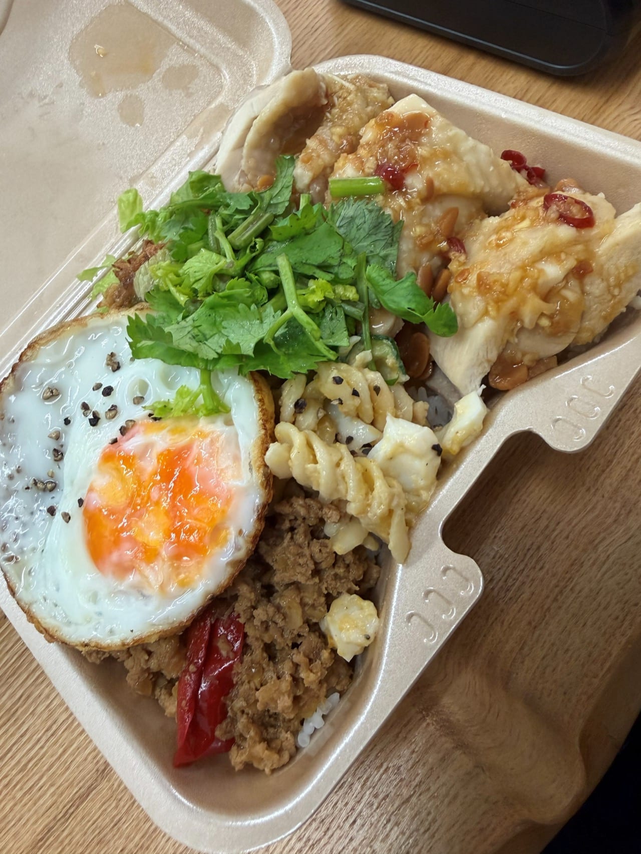 大きな目玉焼きとパクチーがのったダブル弁当のアップ